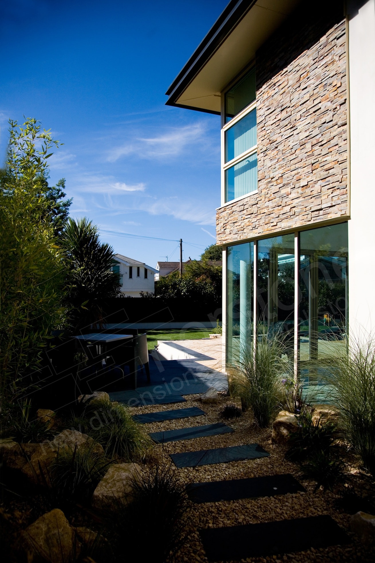 Side View of the corner of a home with a glass corner on the first floor and stone veneer on the second story